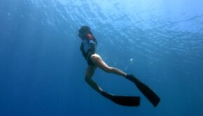 Фридайвер погружается в прозрачную синюю воду