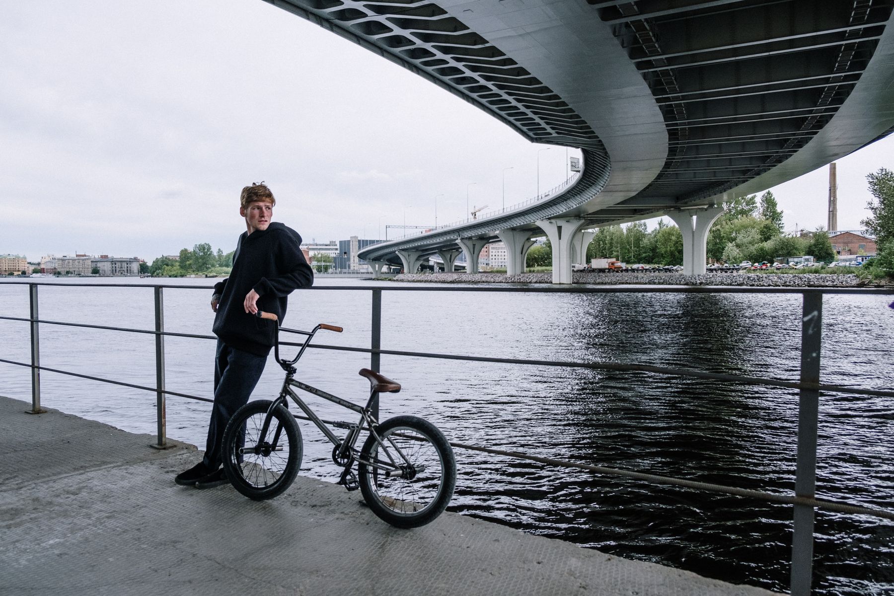 Райдер с BMX у перил под городским мостом